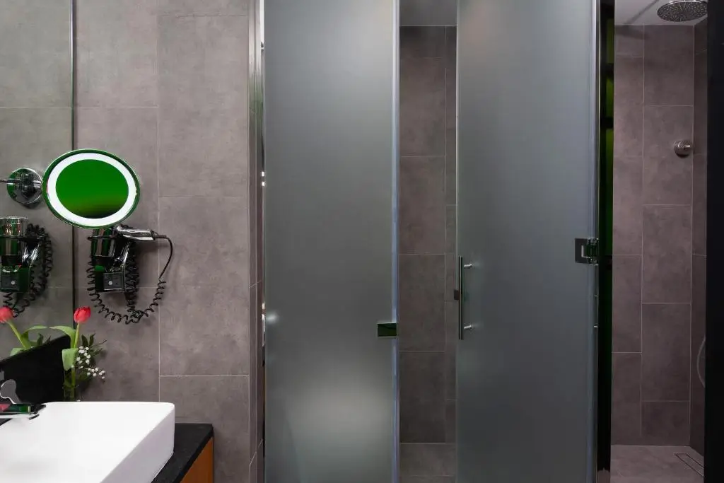 حمام مدرن در اتاق Garden Classic با دوش شیشه‌ای مات، آینه آرایشی و سشوار دیواری